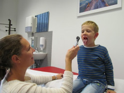 Ärztin leuchtet in Mund eines Jungen