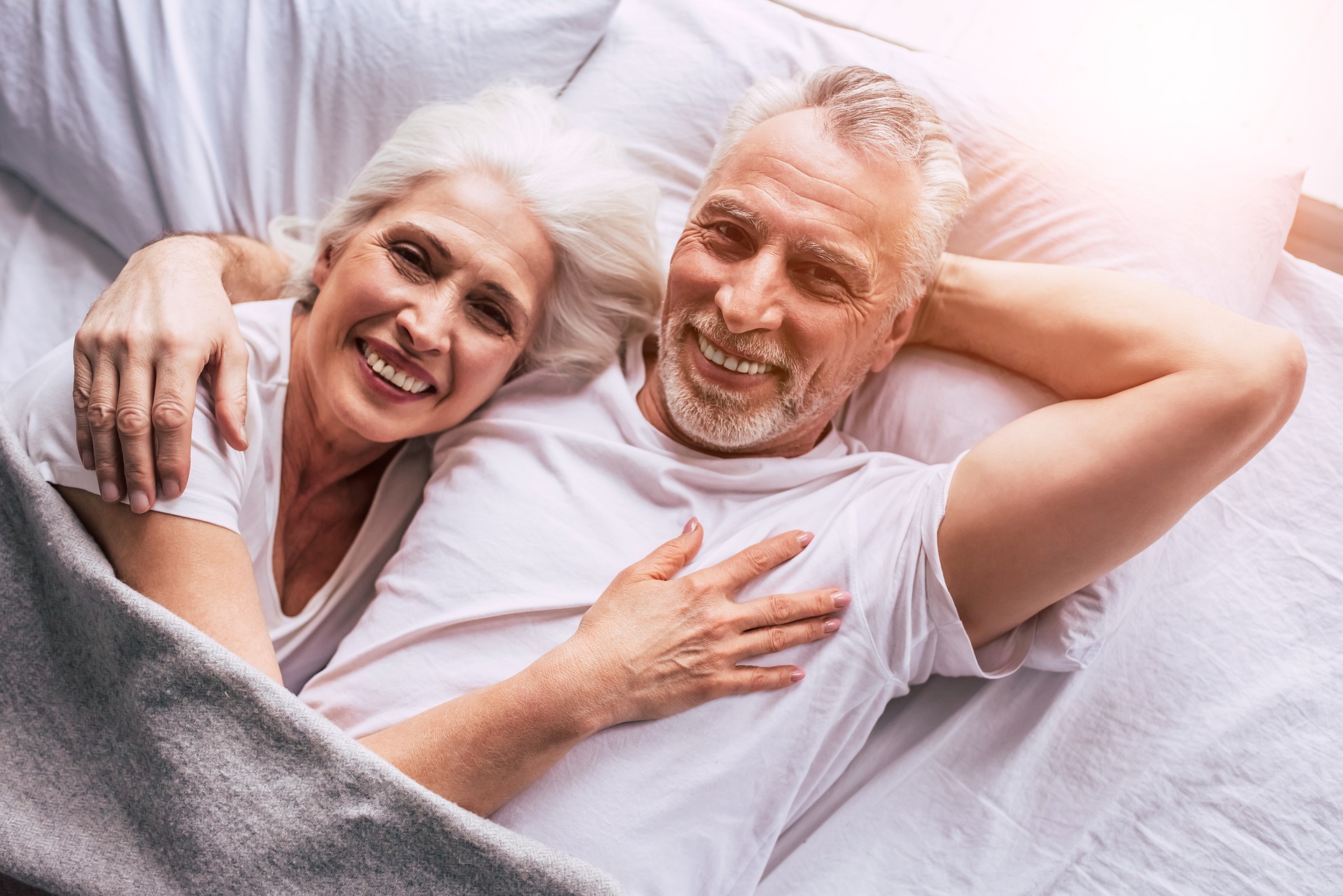 Älteres Paar liegt glücklich nebeneinander im Bett