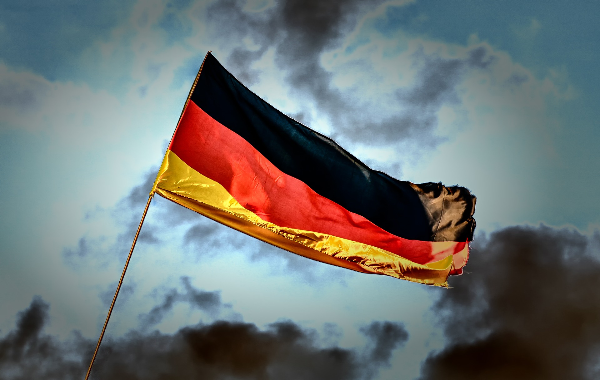 Deutsche Flagge weht vor dunklem Himmel