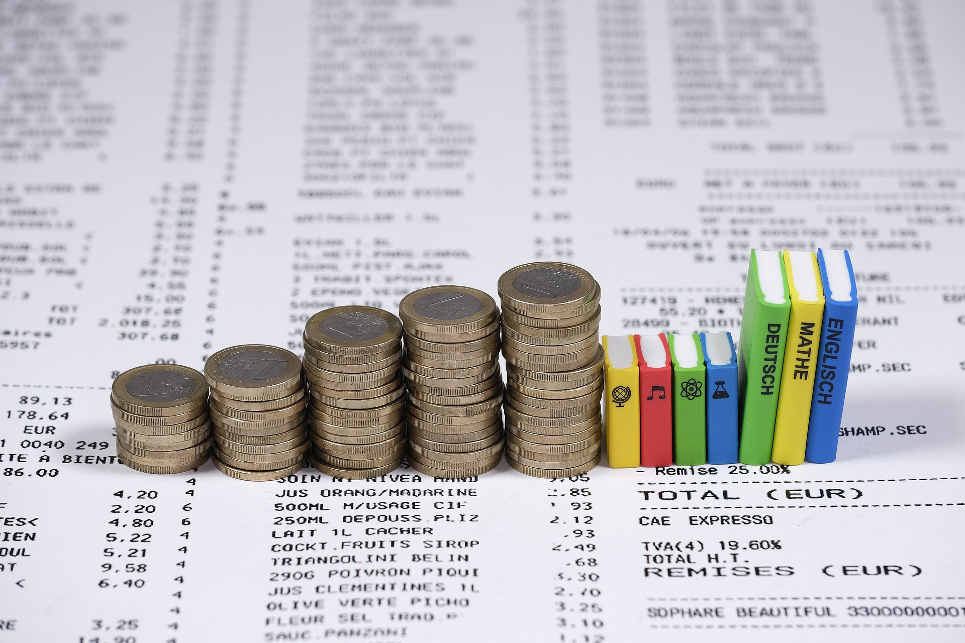 Rechnung, auf der Geldmünzen und modellhafte Schulbücher liegen