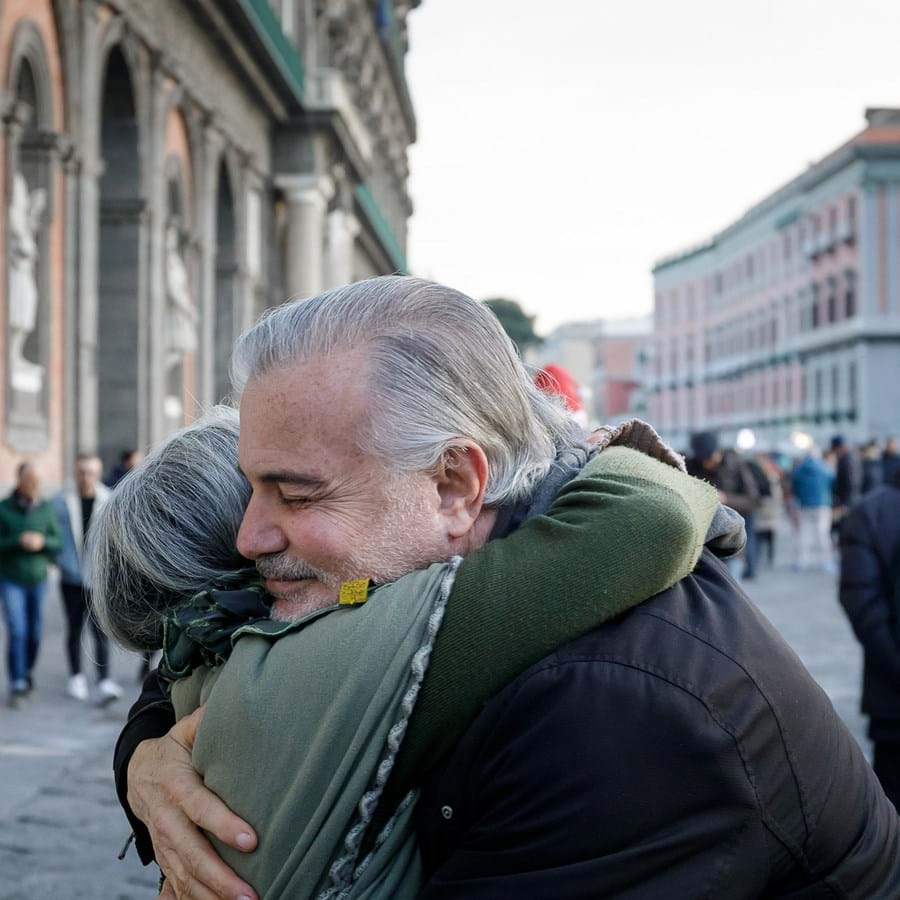 zwei ältere Menschen umarmen sich in einer Fußgängerzone