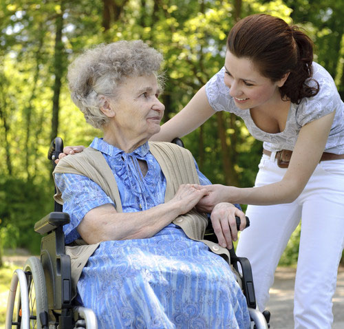 Junge Frau hilft einer Seniorin im Rollstuhl