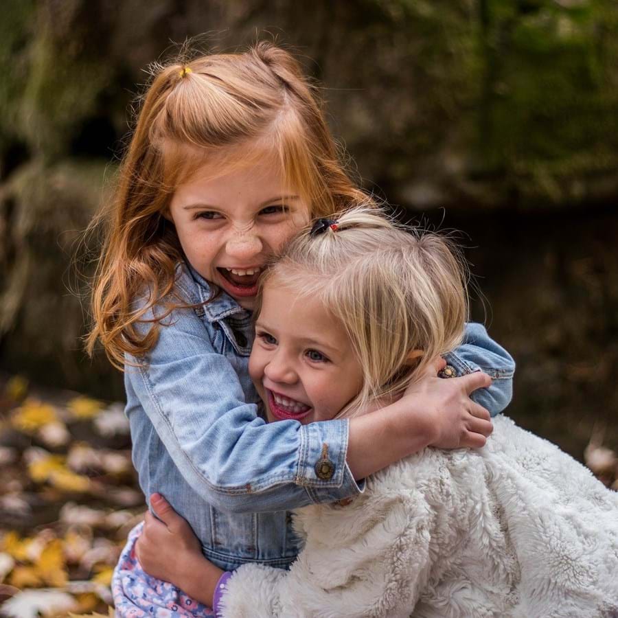 Zwei kleine Mädchen umarmen sich während sie lachen