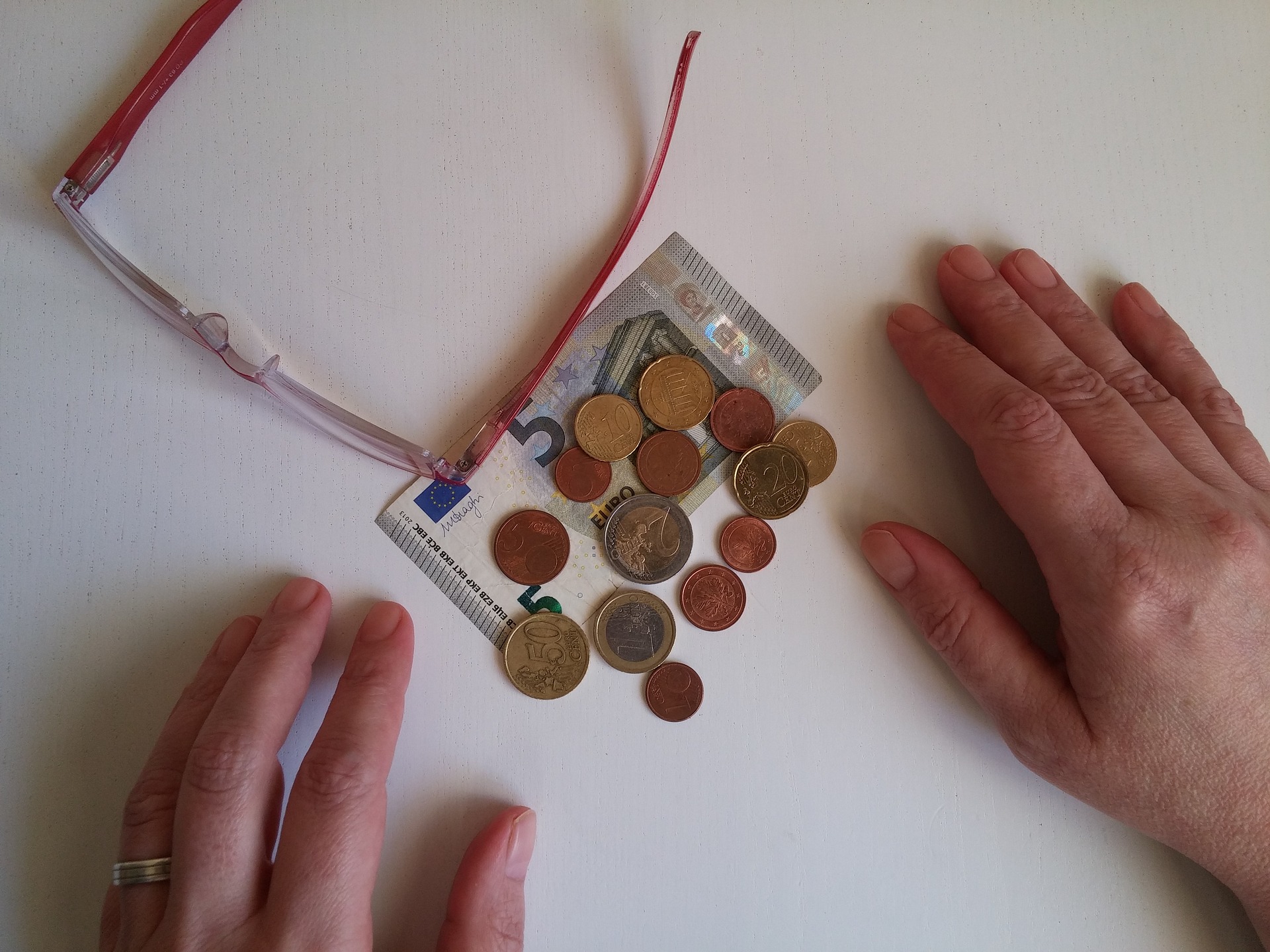 Kleingeld und eine Brille liegen vor zwei Händen