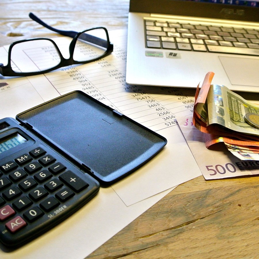 Brille, Taschenrechner, Papiergeld, Akten und ein Laptop
