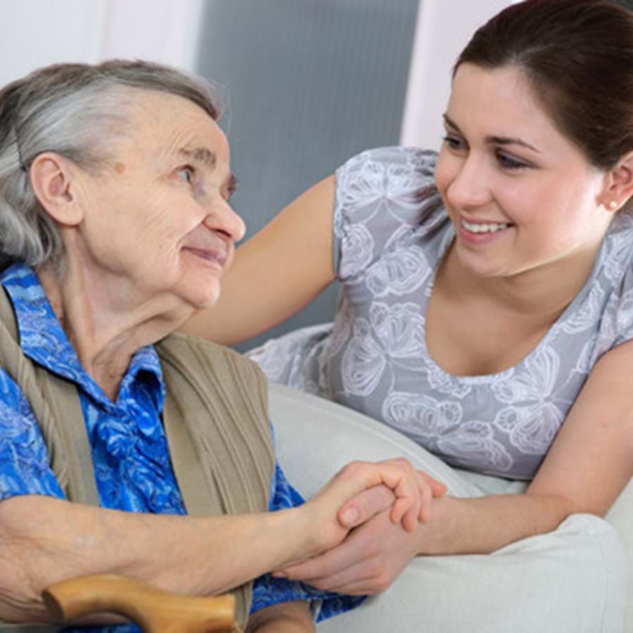 Eine Frau hält die Hand einer älteren Dame während sie sich anlächeln