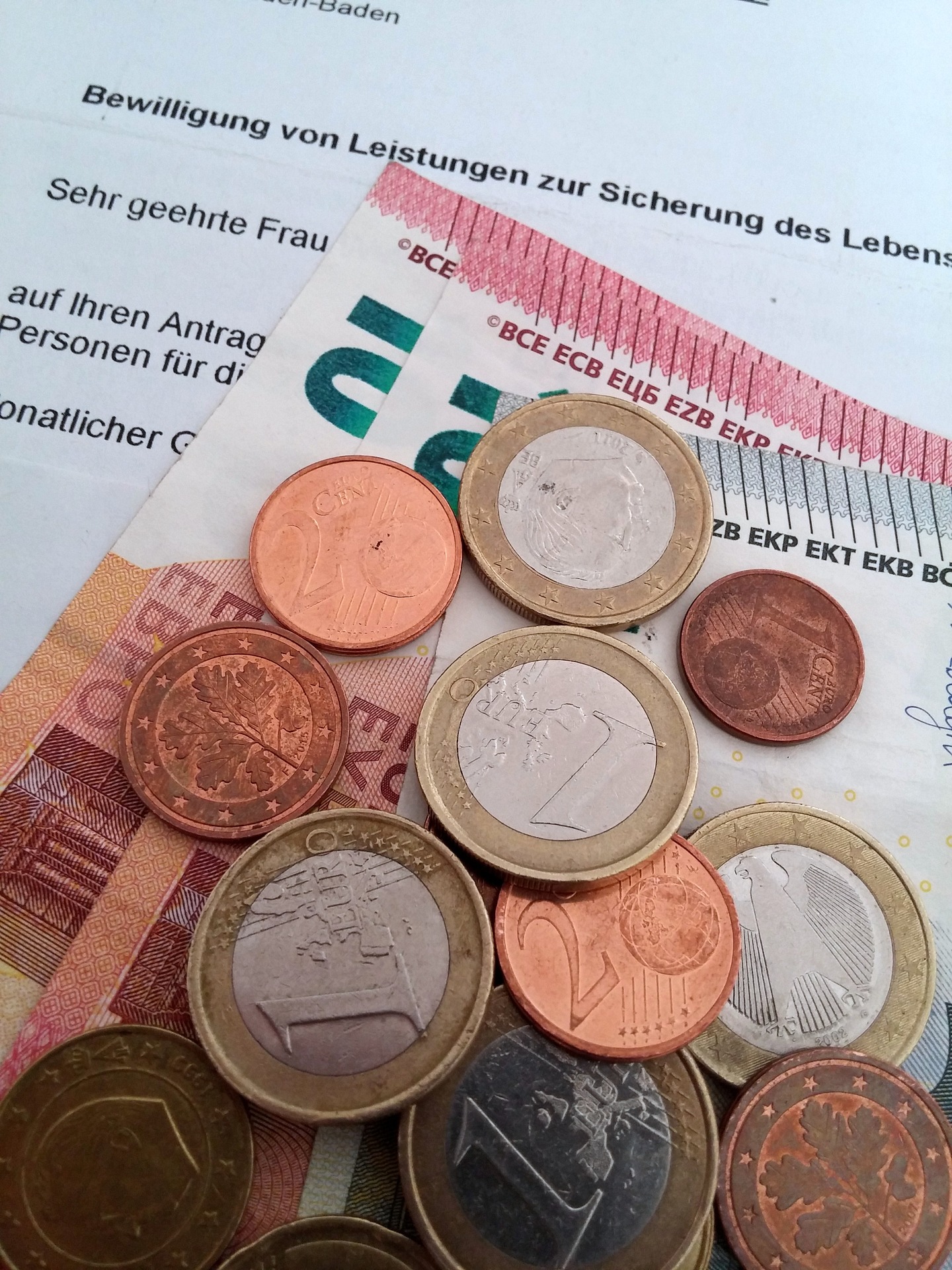 Papier- und Münzgeld liegen auf einem Bescheid