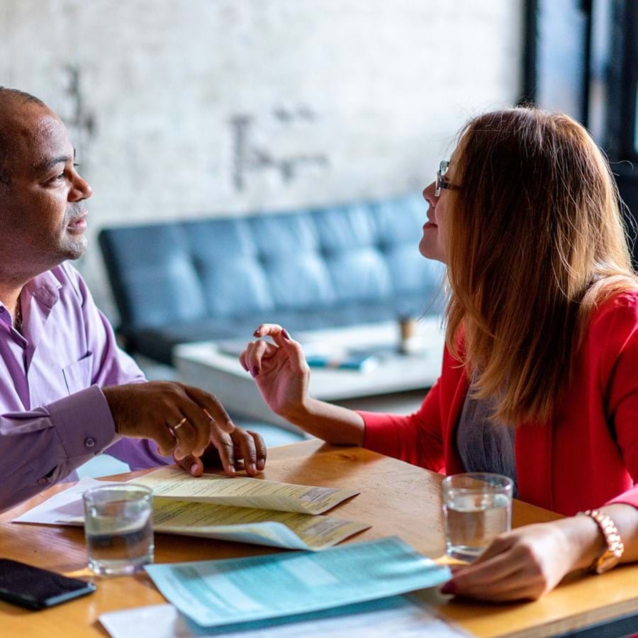 Zwei Personen sitzen am Tisch und besprechen Formulare